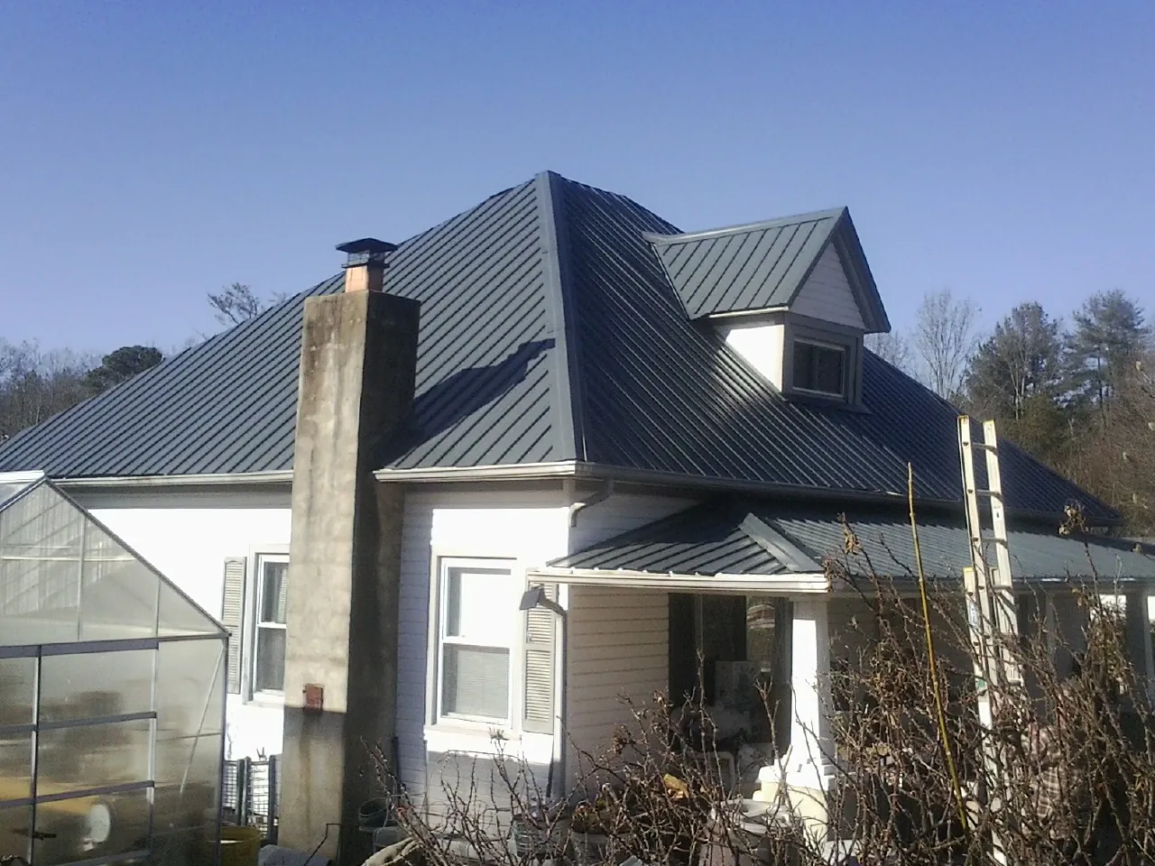 Dark blue standing seam metal roof on a white farmhouse with dormer — Slate & Tile Roof Repair by Roofing Brothers in Potsdam