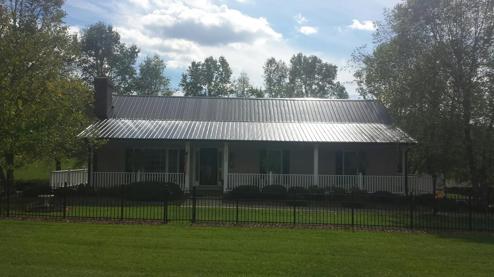 Gray metal roof on a brick ranch with a full width front porch — Gutter Guard Installation work by our crew in Potsdam