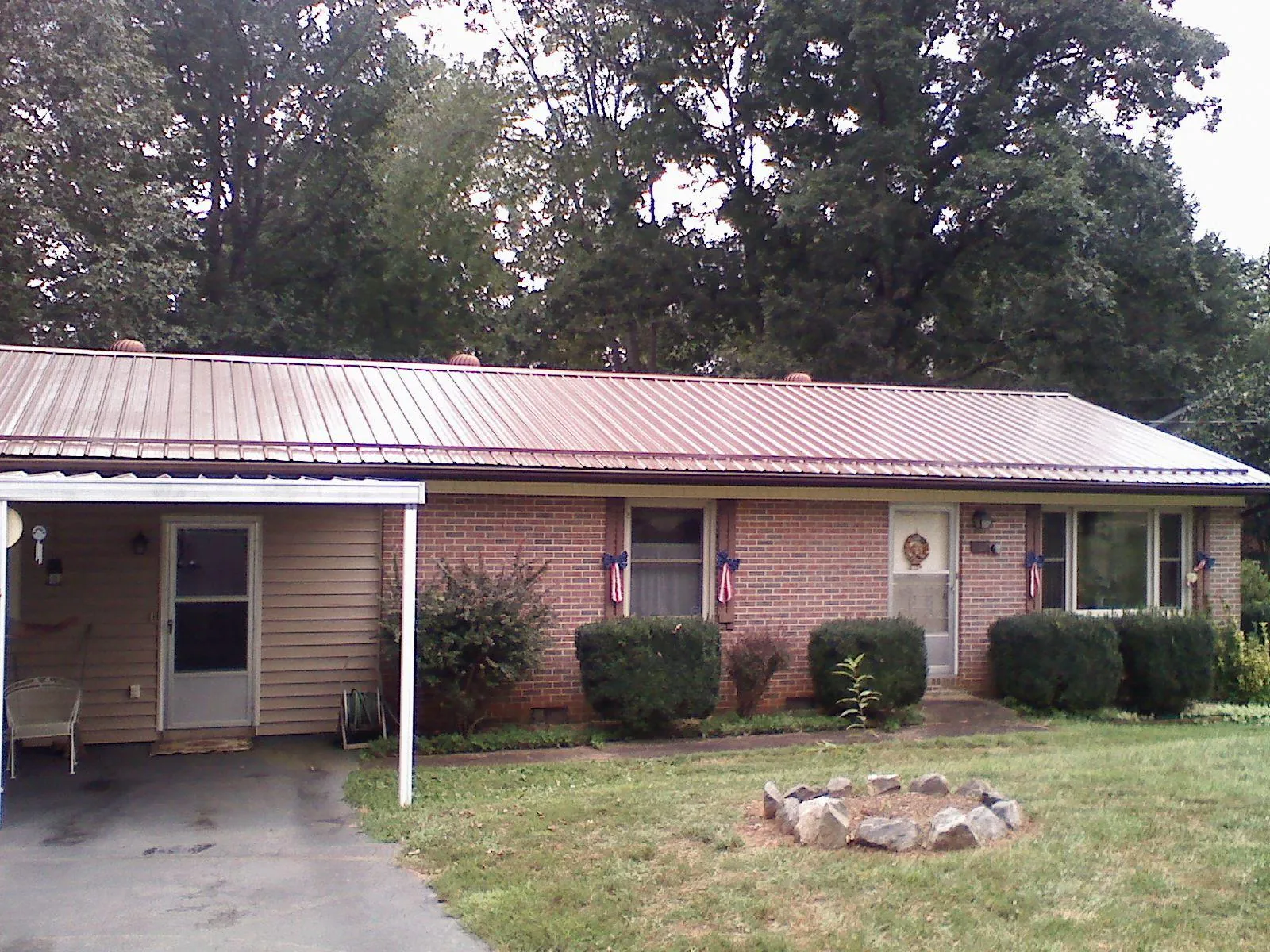 Bronze metal roof and carport on a brick ranch home — Roof Repair work by our crew in Potsdam